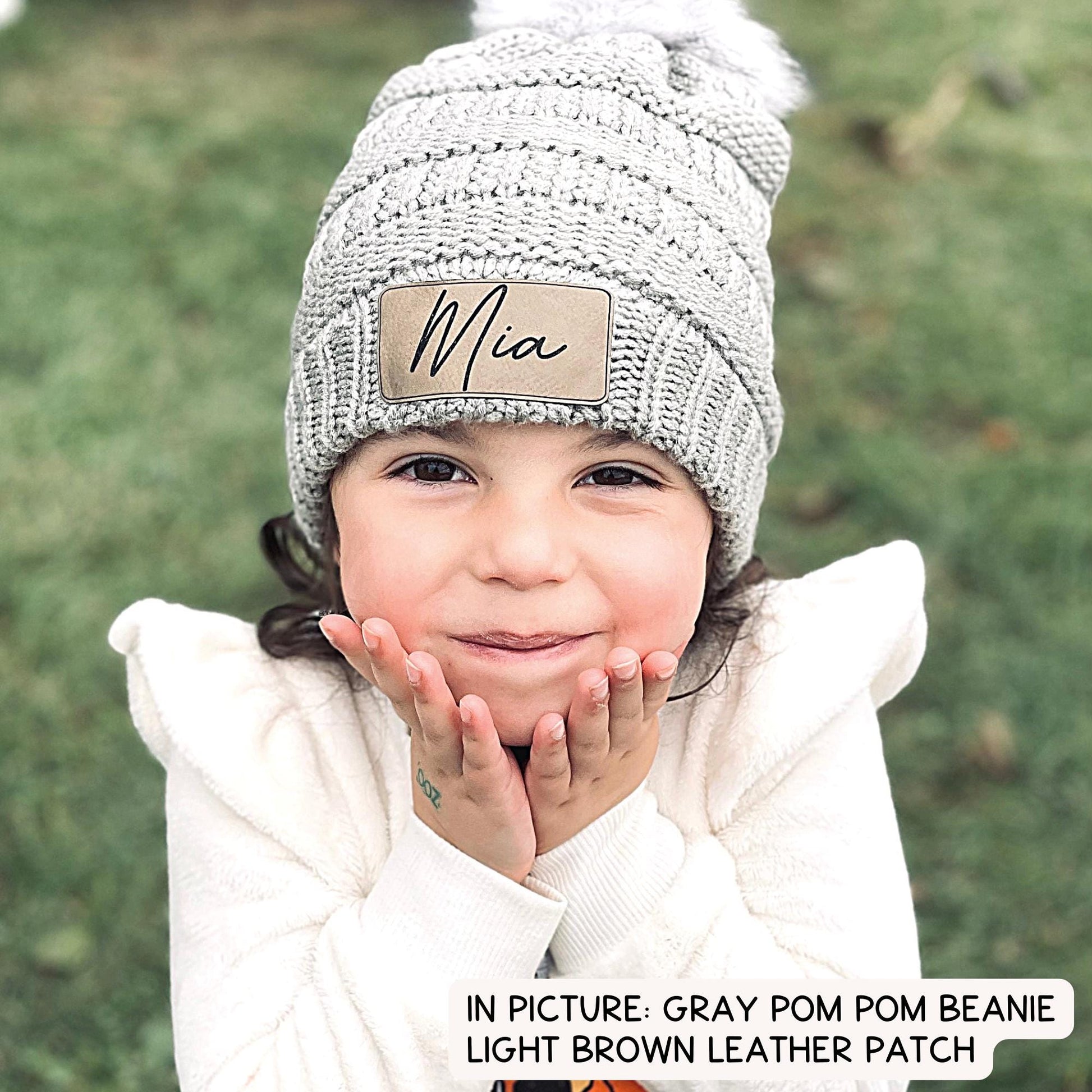 Gray pom pom beanie pictured here with light brown leatherette.